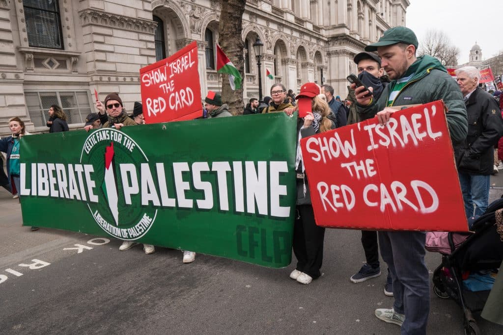 Liverpool and Celtic fans hold up Pro-Palestine signs as they march to the US Embassy.