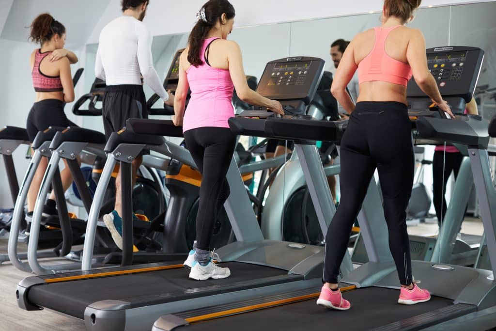 Four individuals, each walking on a treadmill. Each treadmill is occupied.