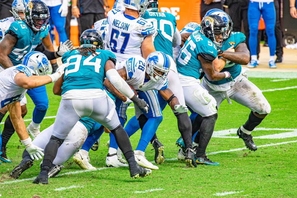 A Detroit Lions player runs through a tackle during a game.