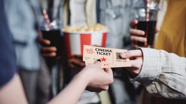 Person handing two movie tickets over to another person.