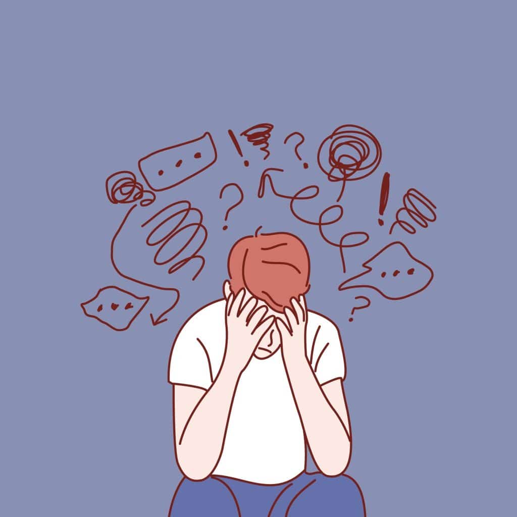 A man with both his hands over his face slumped over as negative scribbles float above his head.