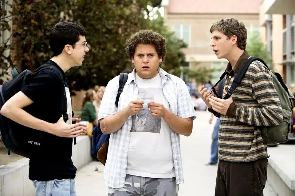 (Left to right) Christopher Mintz-Plasse, Johan Hill, and Michael Cera holding an ID and bickering in Superbad (2007)