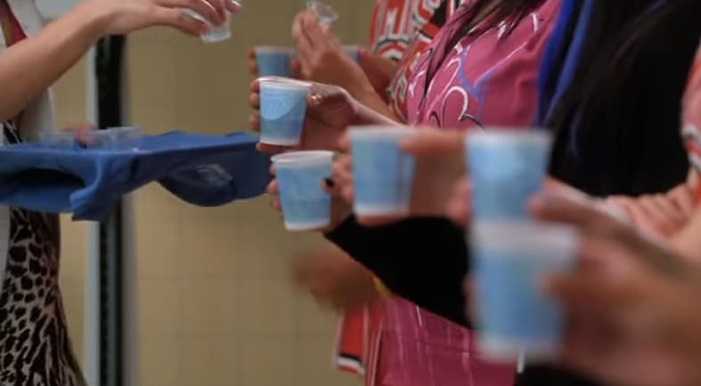 Terri handing the Glee Club tablets in paper cups.