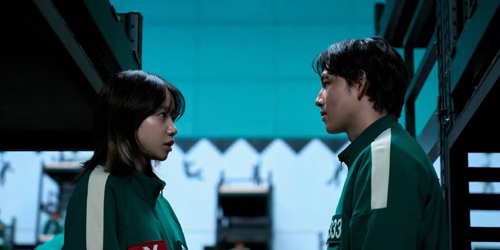 Left Jo Yuri as Jun-hee and right Yim Si-wan as Myung-Gi stare at each other in concern, hiding between bunk beds.