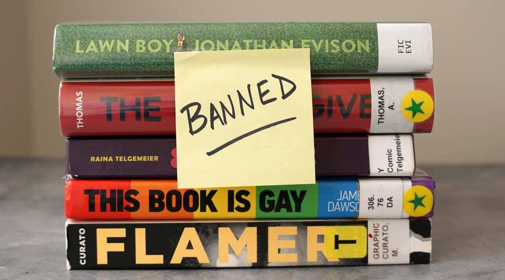 A stack of books found on frequently banned book lists with a sticky note saying "banned". Credit: Shutterstock/MKPhoto12