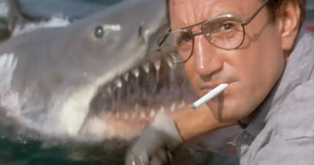 Police Chief Martin Brody (Roy Schneider) with a cigarette in his mouth and a great white shark about to attack in the background. 