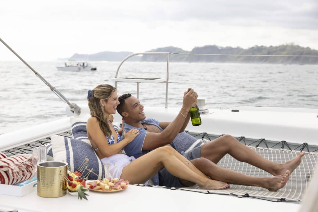 Dale and Kate opening champagne on a catamaran