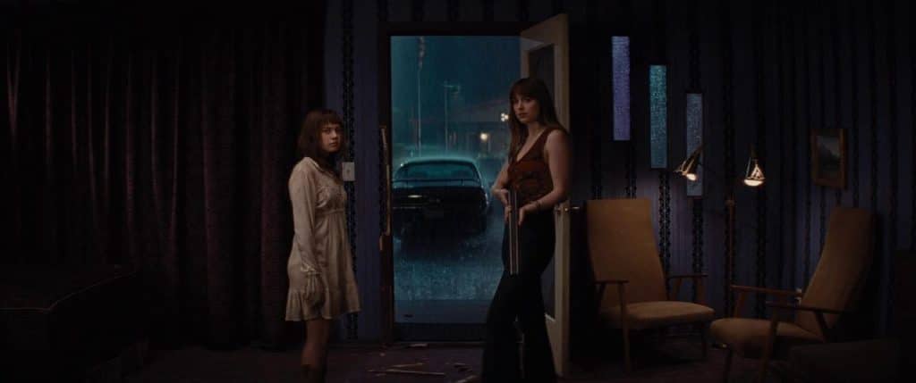 Dakota Johnson's character (Emily Summerspring) holding a shotgun staring at the camera next to her sister, Cailee Spaeny's Rose Summerspring.