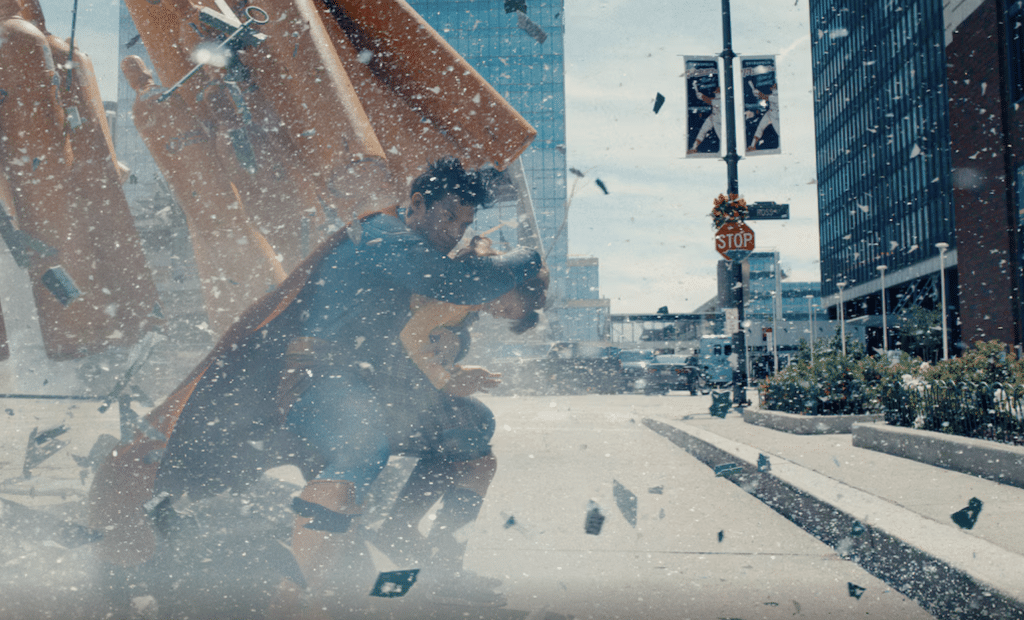 Still from 'Superman' (2025) showcasing the titular hero shielding a girl from incoming debris.