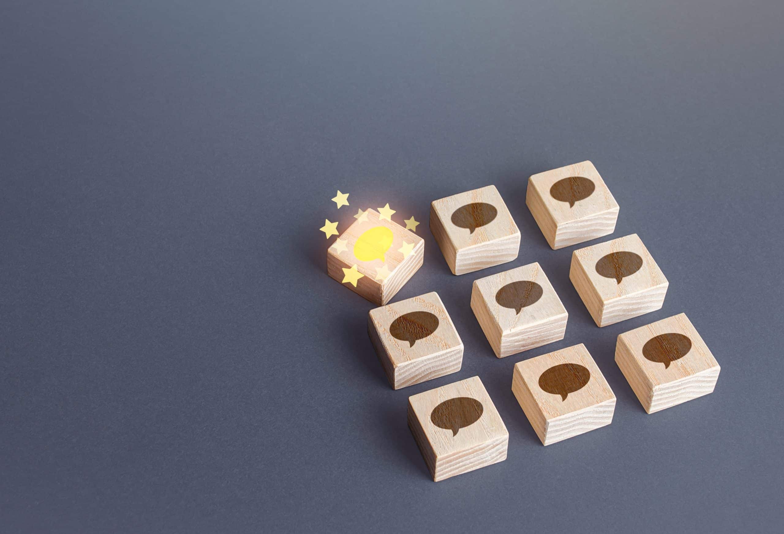 Wooden blocks with speech bubbles on dark blue background (Shutterstock/ Andrii Yalanskyi)