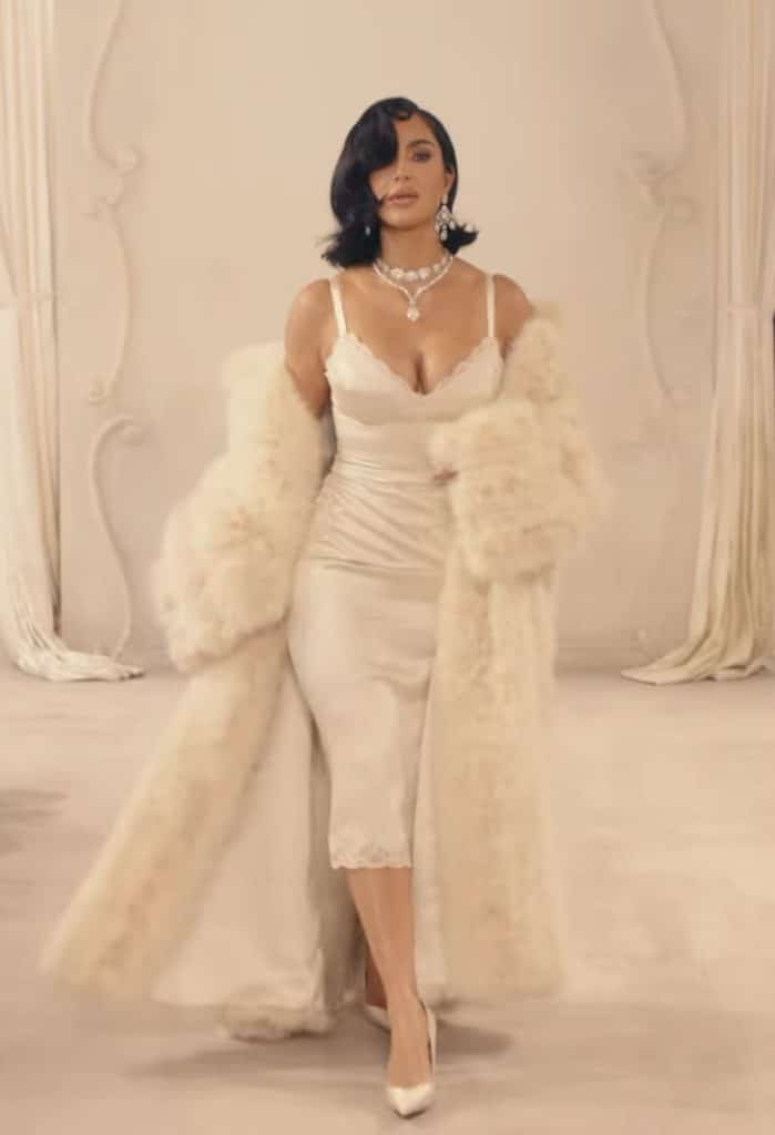 Kim Kardashian walks the runway in a slip dress, while wearing a long, creme colored fur coat.