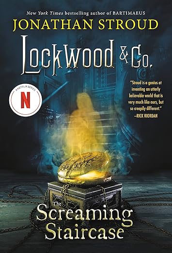 Cover contains a shining gold locket with a shadowed staircase in the background.