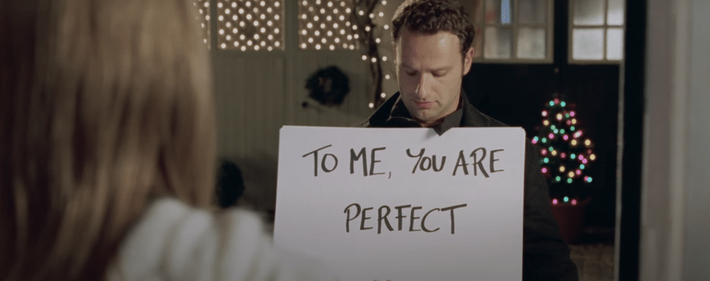 Man holding up sign that says 'to me you are perfect'.