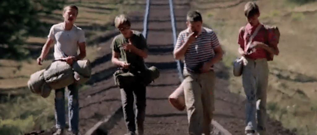 Four boys walking along train tracks.