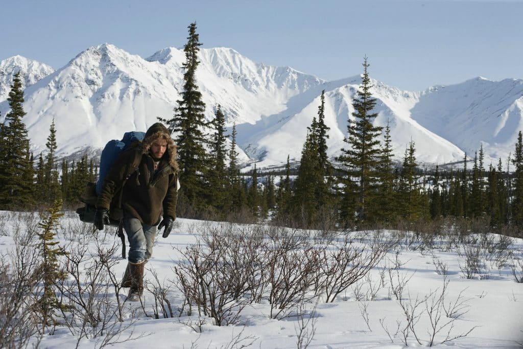 Man walks through the snow with mountains in the background