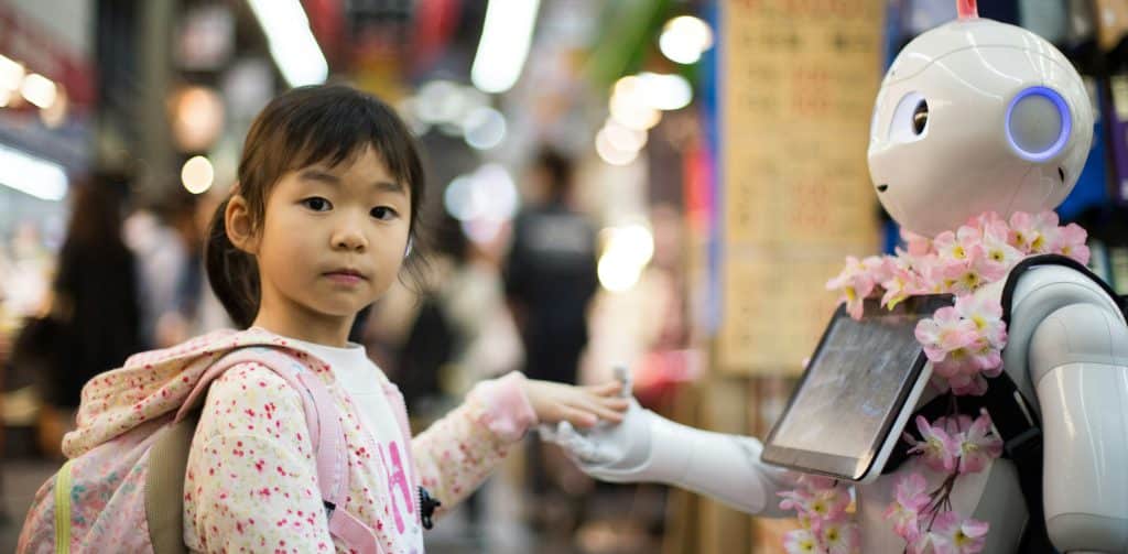 A little girl in Japan shaking hands with a robot