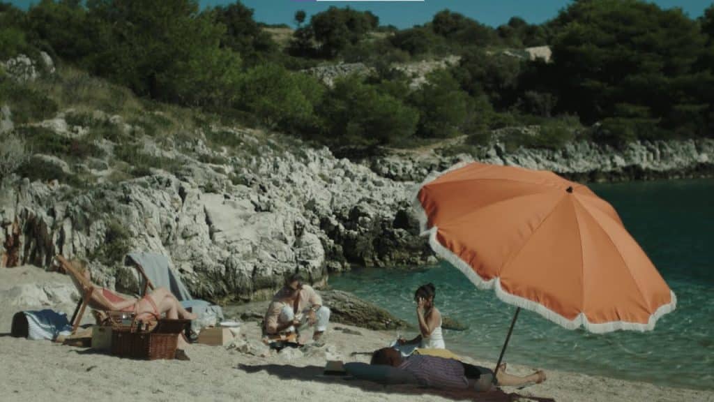 James(Skarsgård), Em (Coleman), and Gabi (Goth) relax on a beach in Infinity Pool.