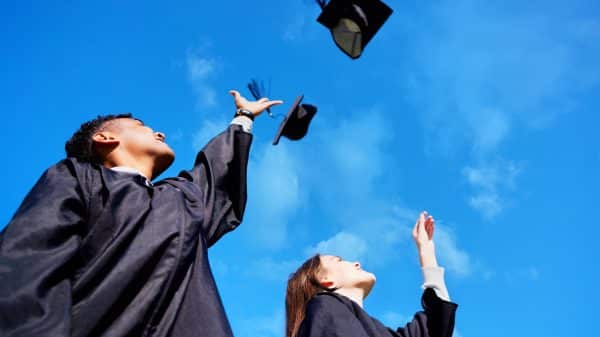 Two graduates throwing their caps in the air.