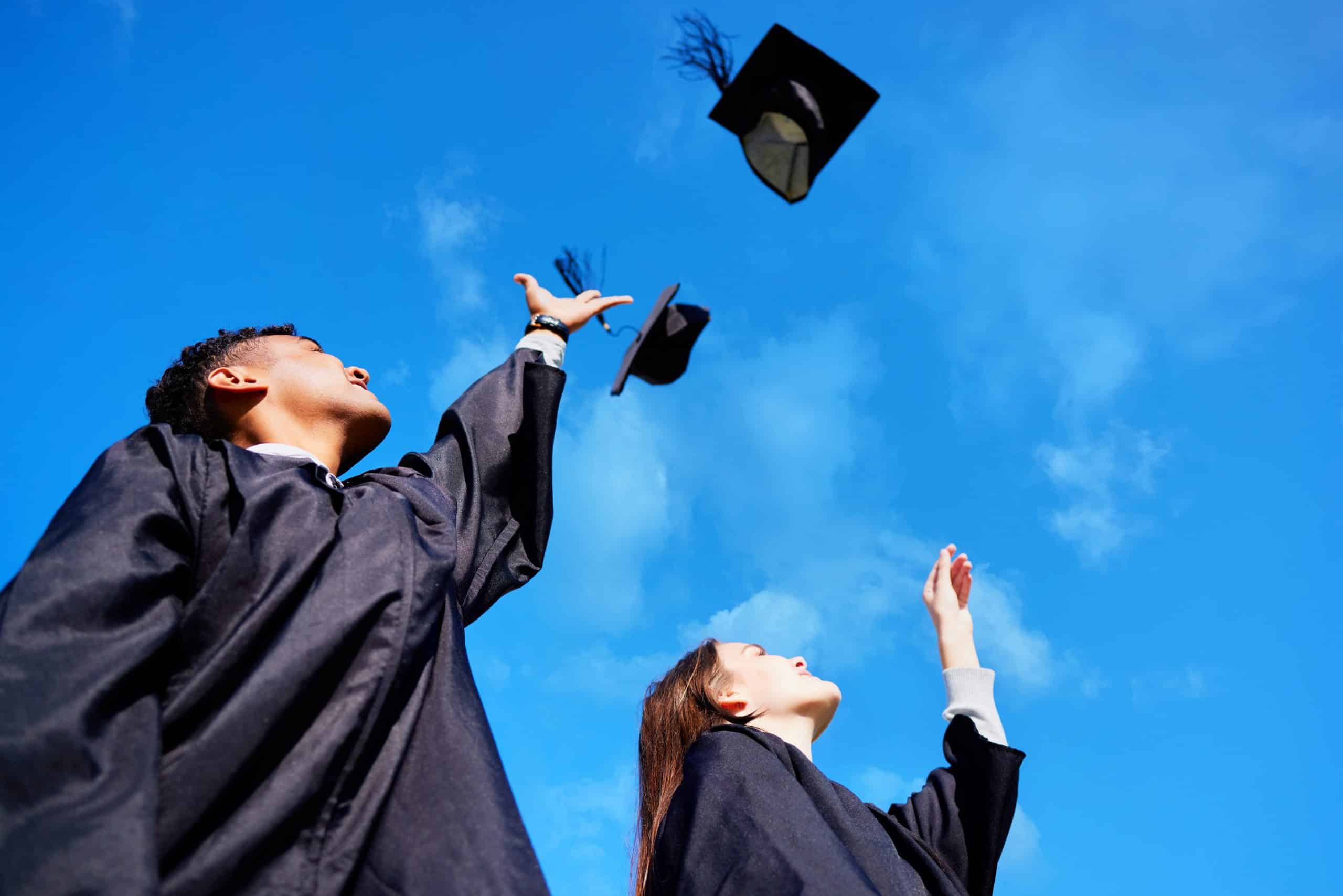 Two graduates throwing their caps in the air.