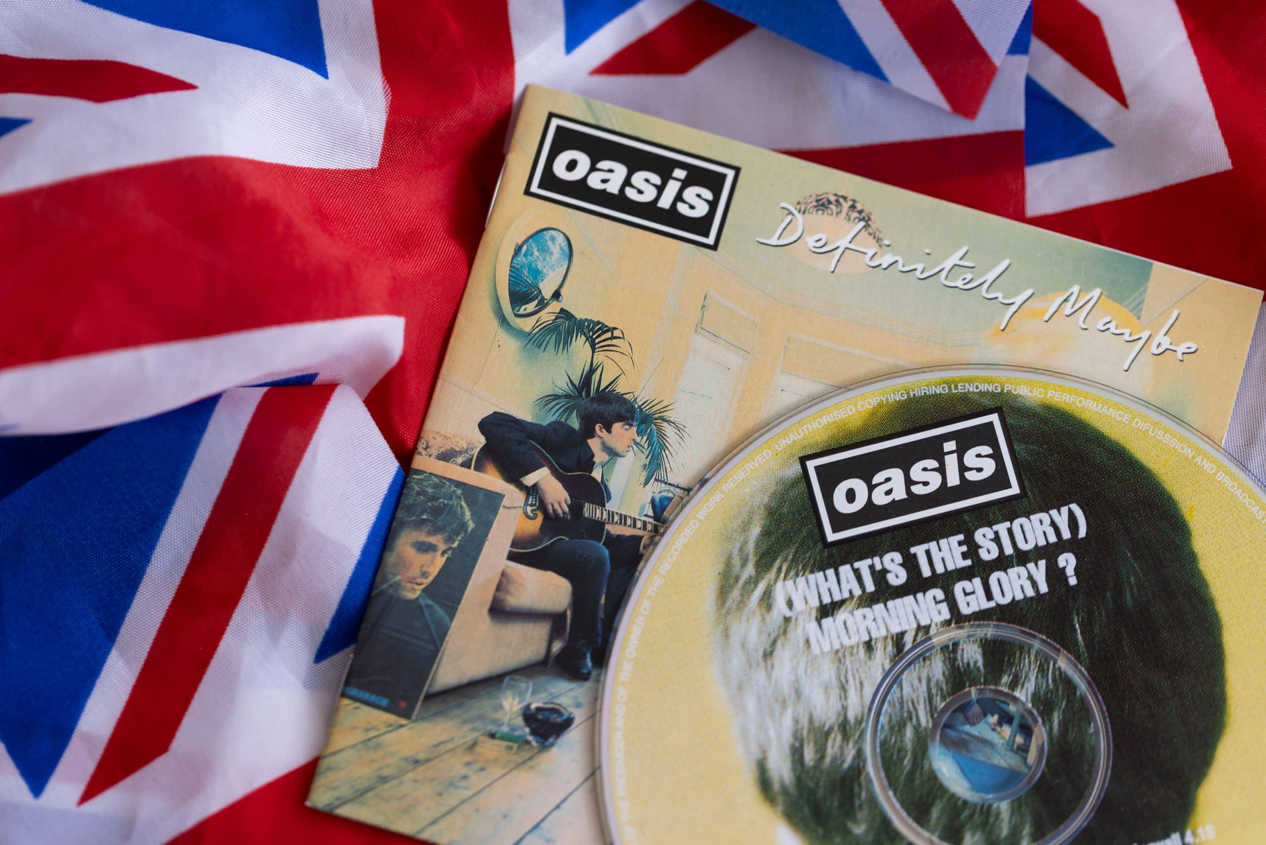 A photo of a flag of the United Kingdom with an Oasis CD of their second album (What's the Story) Morning Glory on top of the flag.