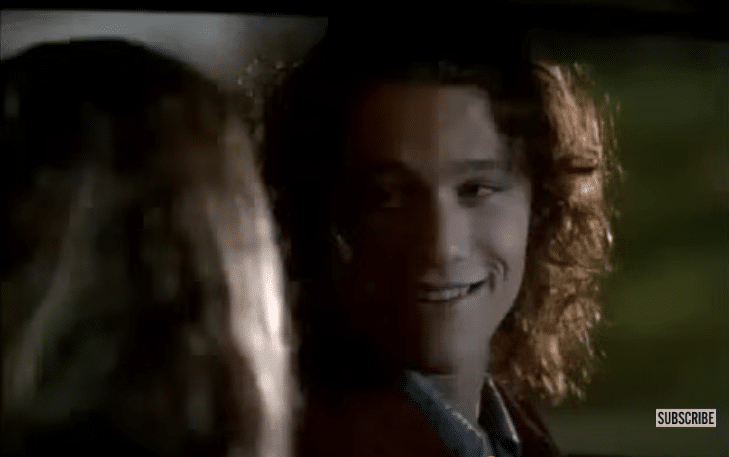 A teenage boy talking to a teenage girl in a car. She is facing away from the camera.