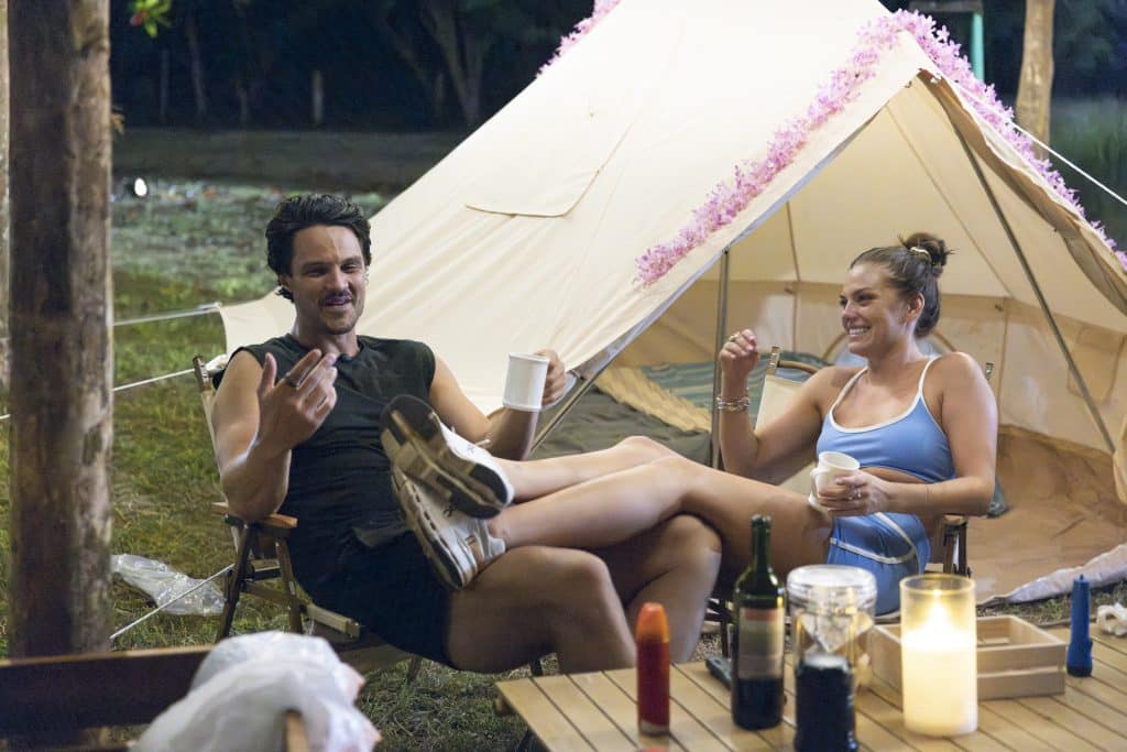 Spencer and Jess sit together in front of a tent.