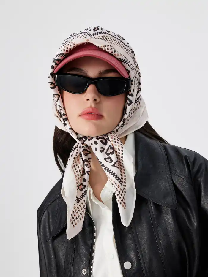 Chic woman wearing a leopard print bandanna over a pink hat. (Credit: Cider)