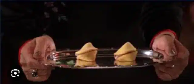 Woman holds two fortune cookies on a platter.