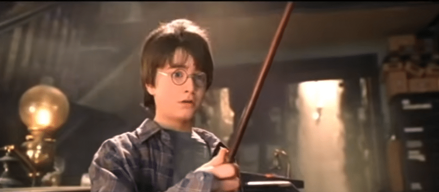 A boy holding a magic wand and looking at it in awe.