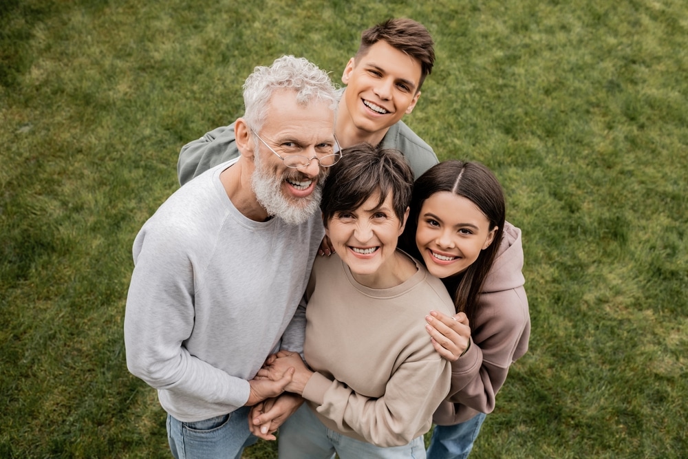 Family photo of mother, father, sister, and brother, all smiling, taken at a high angle outside.