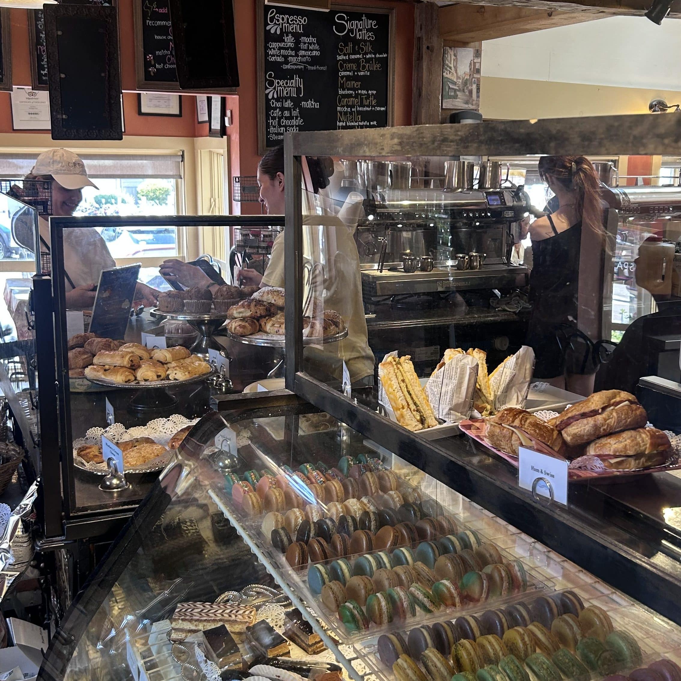 The display case at Mornings in Paris filled with baked goods, such as macarons, cakes, and pastries.