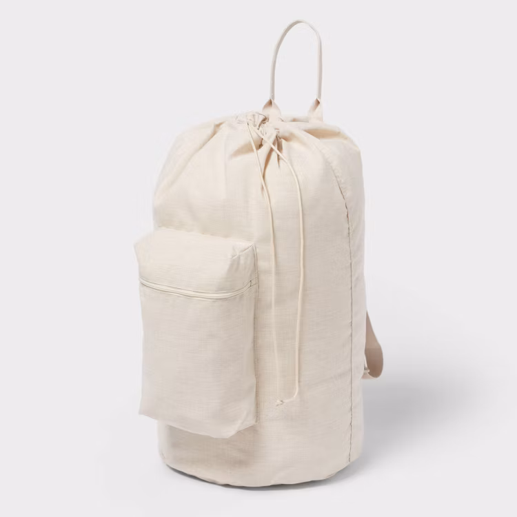 Beige laundry backpack featuring front pouch with a zipper.