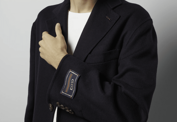 A black wool Gucci coat, with the neck tag sewn into the wrist part of the sleeve.