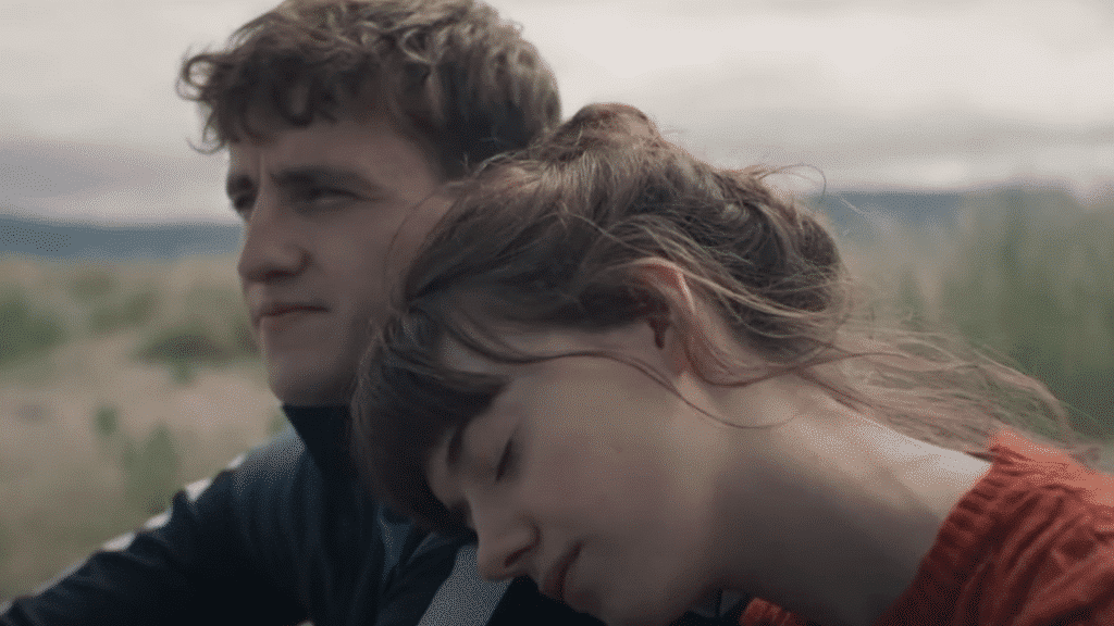 A man and woman sitting in a grassy field.