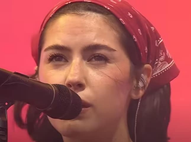 Gracie Abrams wearing a maroon bandanna during her 2025 debut at Glastonbury. (Credit: BBC Music YouTube)