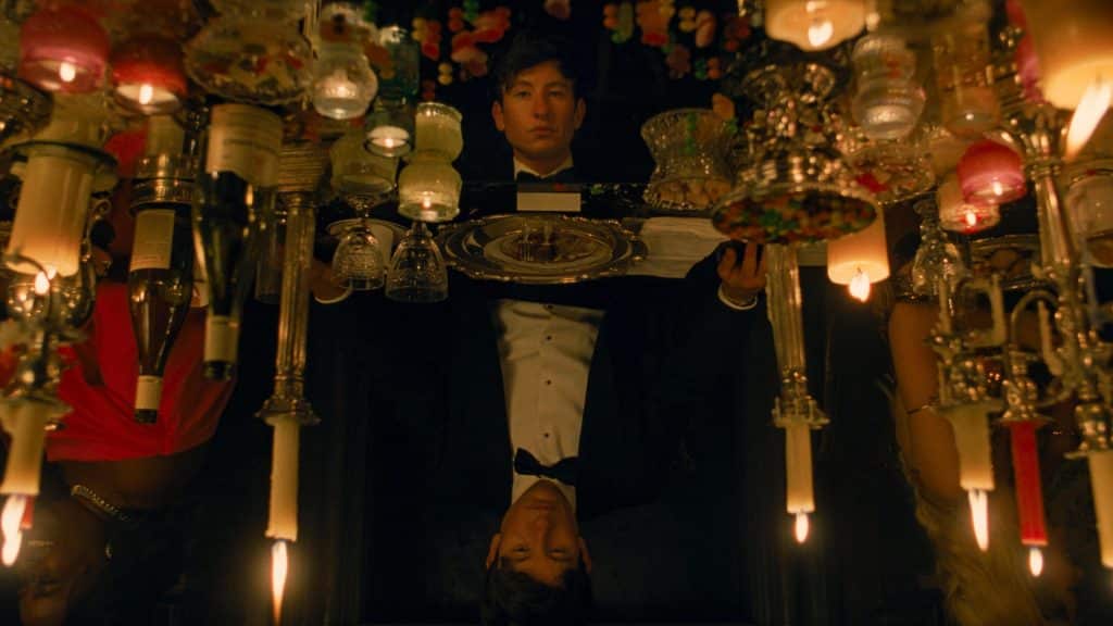 Oliver's reflection appears on the dinner table surrounded by candles.