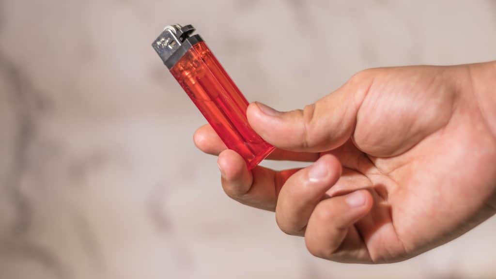 Hand passing a lighter.