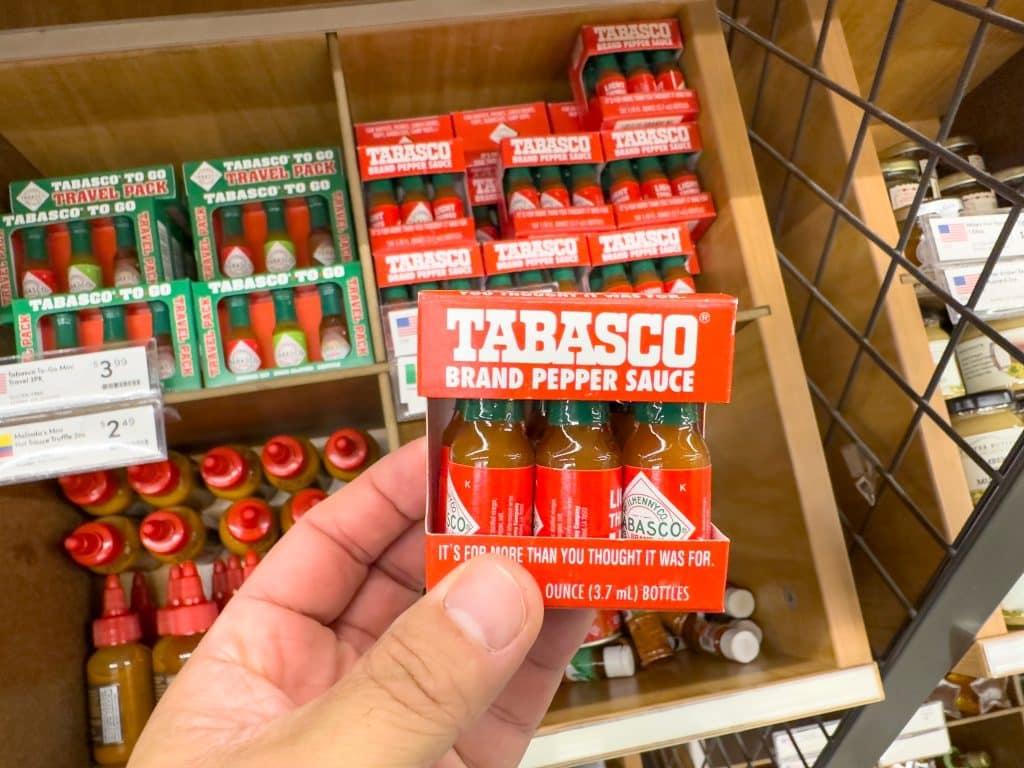 Man holds a container of mini-Tabasco bottles.