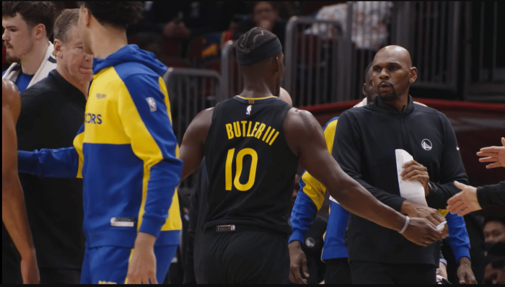 Jimmy Butler walks to the bench, surrounded by new coaches and staff from the team who traded for him at the deadline. (Golden State Warriors/YouTube)