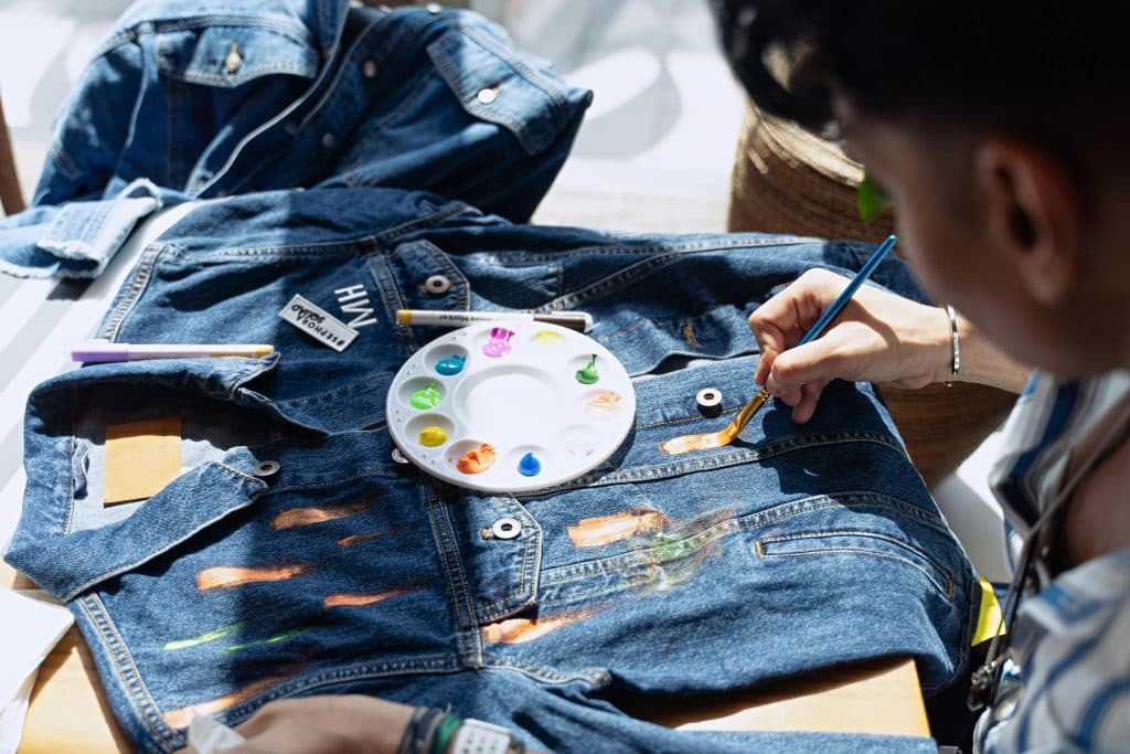A person painting a denim jacket