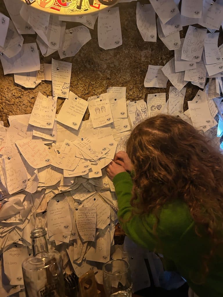 Person pinning note on wall at For Sale Pub Budapest