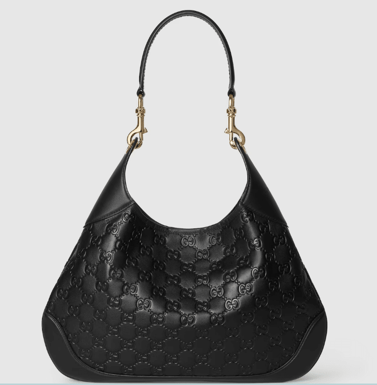 black slouchy bag with gucci logo pressed repeatedly into the leather, pictured on a gray background
