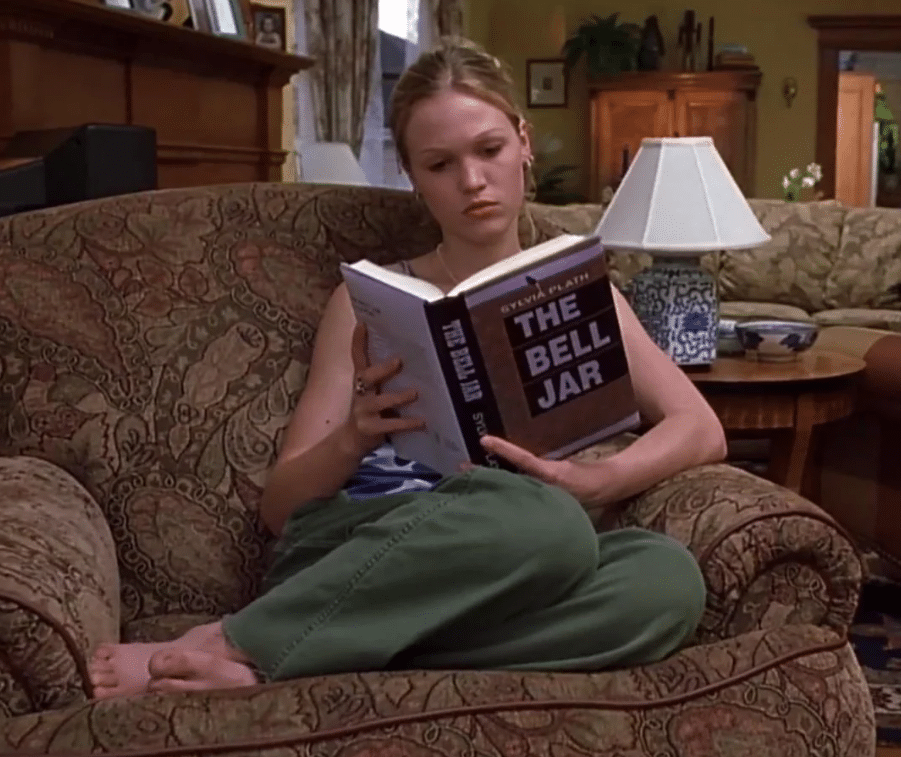 Girl reading Sylvia Plath's 'The Bell Jar' on a couch.