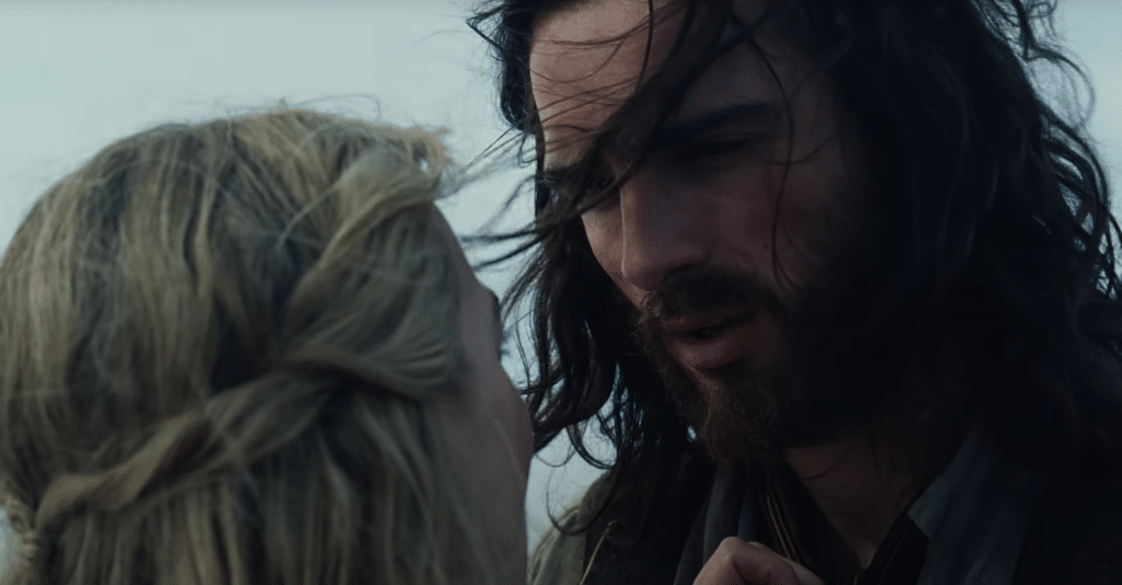 Heathcliff leans into talk to Catherine, while the wind blows their hair.