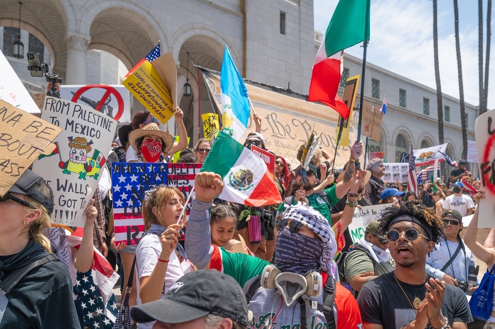 Los Angeles protesters holding signs with slogans during the No Kings protest, opposing Trump's immigration policies.