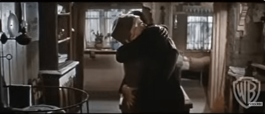 A woman and man embracing in a kitchen.