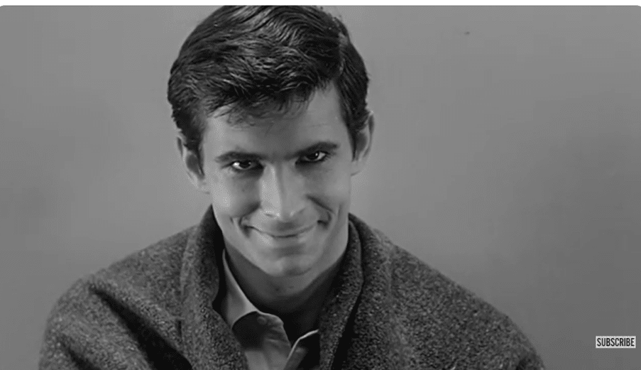 A man stares at the camera, smiling in a sinister way.