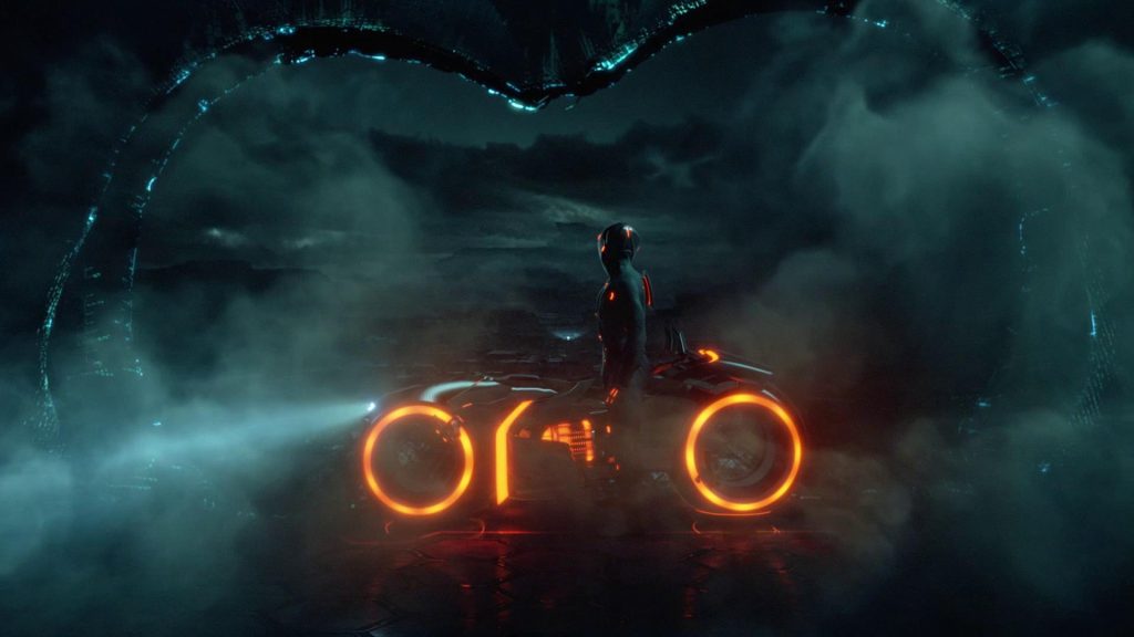Rinzler, a man in black armor with an orange glow, staring at the vast expanse of The Grid with his glowing orange Light Cycle at his side.