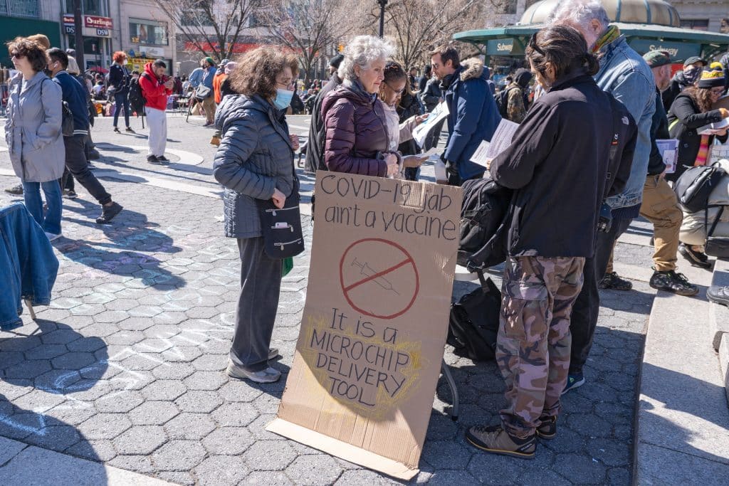A sign is propped up amongst a rally promoting a conspiracy theory that the COVID-19 vaccine is used to microchip citizens to surveil them.