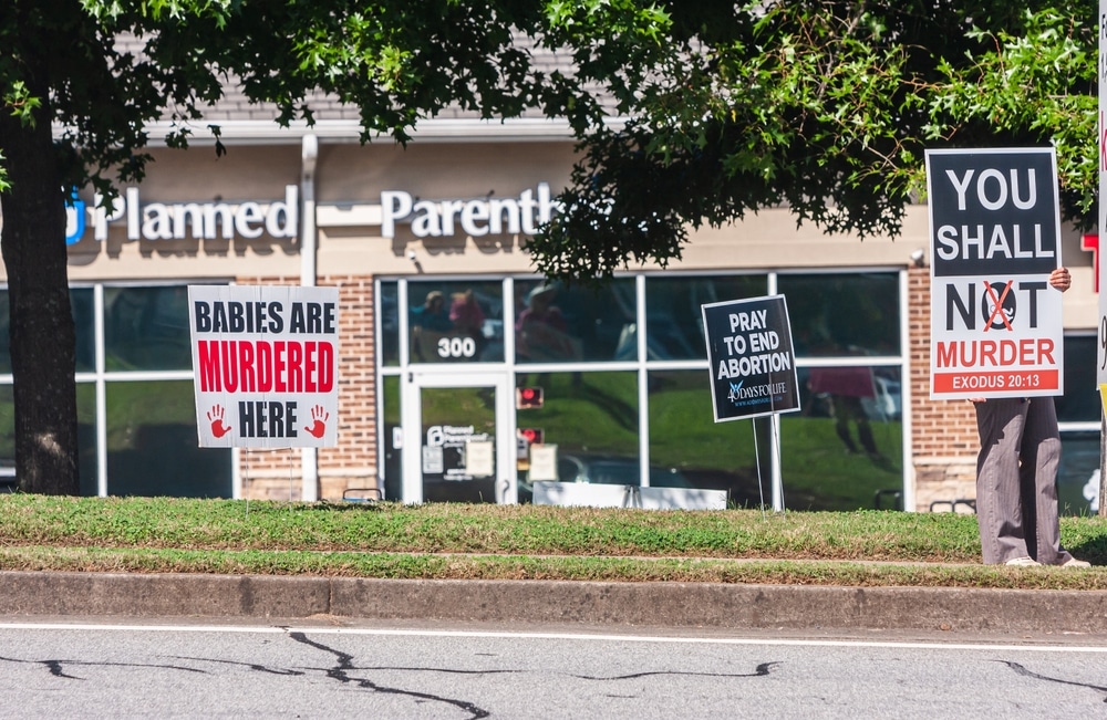 Image shows protests outside a Planned Parenthood clinic in Georgia, with placards readings 'Pray to end abortion, and 'Babies are murdered here,' for example.